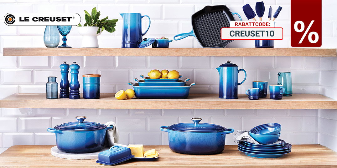 Le Creuset Küchenserie in Blau stilvoll auf offenen Holzregalen präsentiert