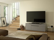 Modernes TV-Lowboard in grauer Farbe, frontal betrachtet, mit großem Flachbildfernseher darauf, in einem stilvoll eingerichteten Wohnzimmer.