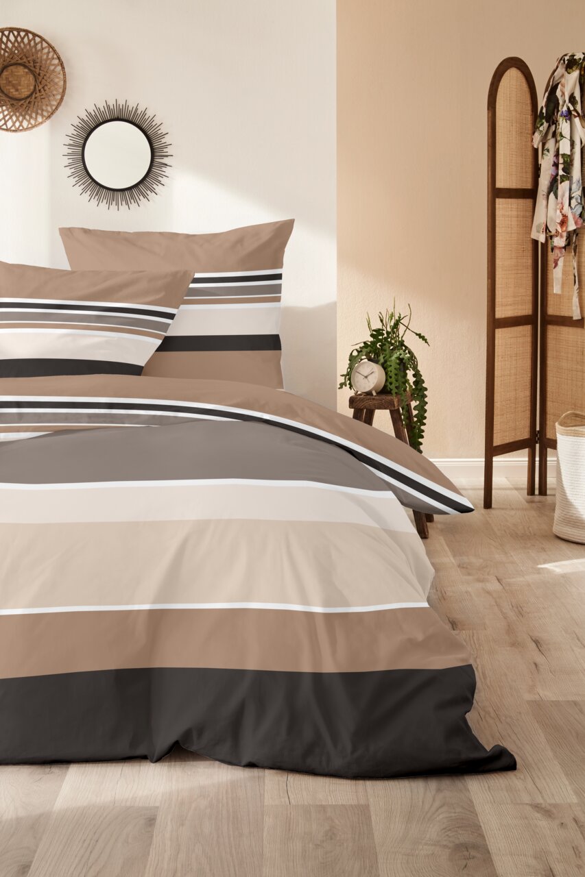 Primera Mako Satin Bettwäsche 135/200cm SATIN Gestreifte Bettwäsche in Beige, Taupe, Grau und Schwarz mit zwei Kissen auf einem Bett, seitliche Perspektive im Schlafzimmer-Setting