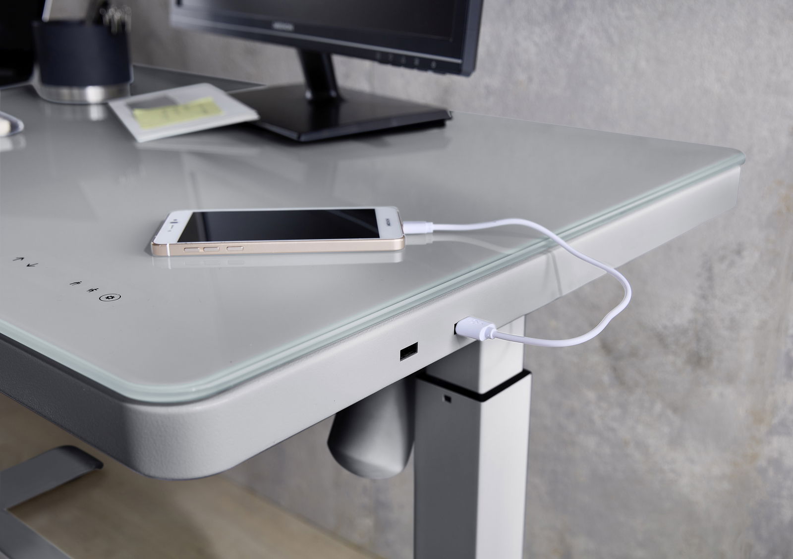 Moderner E-Schreibtisch mit Glasoberfläche, USB-Anschluss und Smartphone, seitliche Perspektive