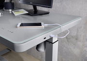 Moderner E-Schreibtisch mit Glasoberfläche, USB-Anschluss und Smartphone, seitliche Perspektive