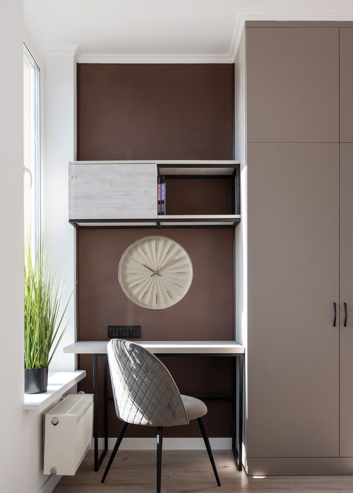 Moderne Wanduhr in einem stilvollen Arbeitsbereich, frontal betrachtet. Die Uhr hat ein minimalistisches Design und ist in einem Regal über einem Schreibtisch platziert.