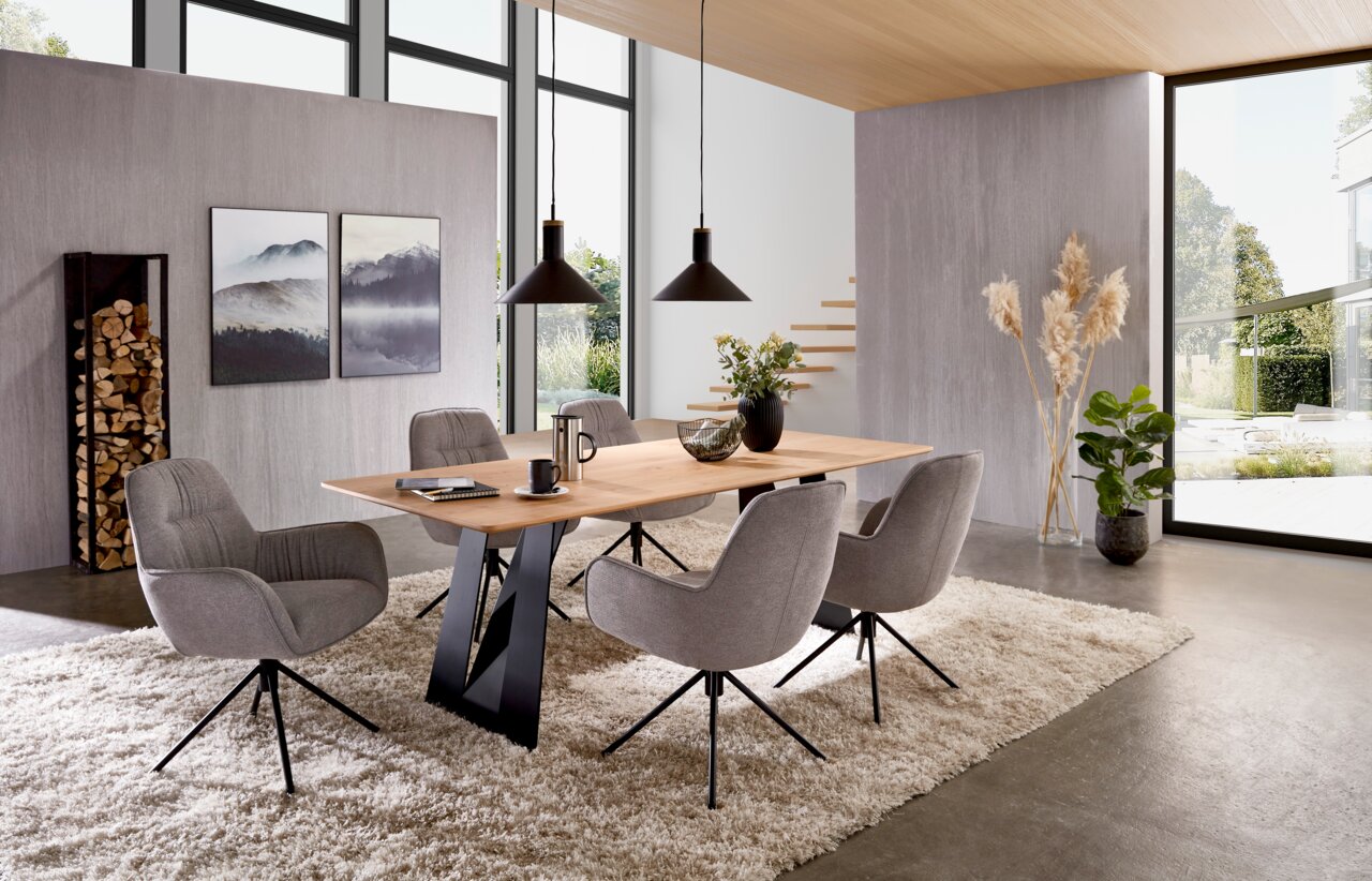 Wöstmann Markenmöbel Eettafel WM 2320 Moderne eethoek met een rechthoekige eettafel van licht hout en zwarte metalen poten, omringd door vier grijze gestoffeerde stoelen op een beige hoogpolig tapijt, gefotografeerd vanuit een licht verhoogd, schuin vooraanzicht.