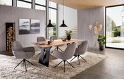 Moderne eethoek met een rechthoekige eettafel van licht hout en zwarte metalen poten, omringd door vier grijze gestoffeerde stoelen op een beige hoogpolig tapijt, gefotografeerd vanuit een licht verhoogd, schuin vooraanzicht.