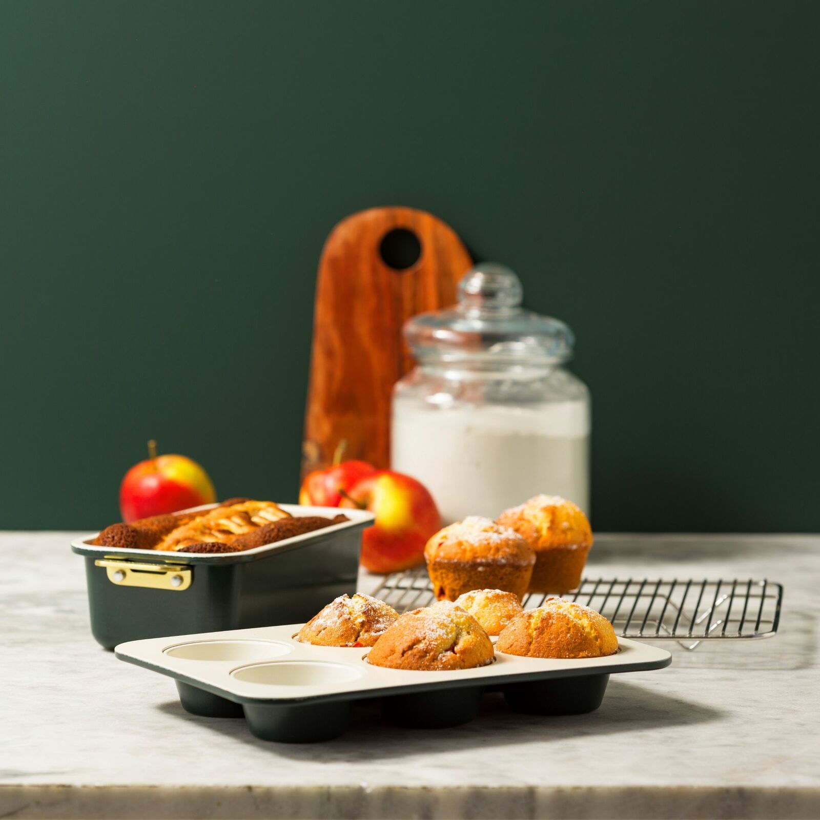 Backformen Set 6-tlg. mit Muffins und Kuchen, seitliche Perspektive auf einem Küchentisch mit Äpfeln und Mehlglas im Hintergrund.