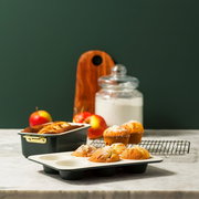 Backformen Set 6-tlg. mit Muffins und Kuchen, seitliche Perspektive auf einem Küchentisch mit Äpfeln und Mehlglas im Hintergrund.