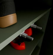 Nahaufnahme eines Schuhschranks mit einem schwarzen Stiefel und roten Schuhen auf den Regalen, seitliche Perspektive