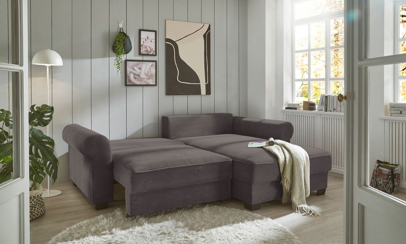 Graue Rundecke in einem hellen Wohnzimmer, seitliche Perspektive