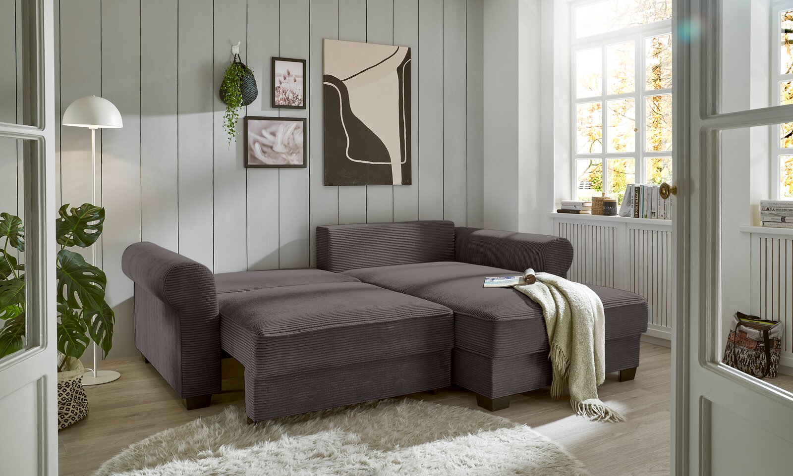 Graue Rundecke in einem hellen Wohnzimmer, seitliche Perspektive