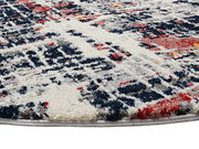 Nahaufnahme eines Designer-Teppichs mit abstraktem Muster in Blau, Rot, Grau und Weiß, perspektivisch von der Seite aufgenommen.