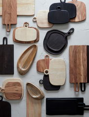 Verschiedene Schneidebretter aus Holz in unterschiedlichen Formen und Farben, von oben betrachtet.