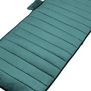 Gepolsterte, gesteppt wirkende Sitzauflage in Petrol/Türkis mit Kissen am Kopfende, schräg von oben in Nahaufnahme auf weißem Hintergrund