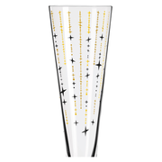 Nahaufnahme eines Champusglases mit goldenen und schwarzen Sternmustern auf transparentem Glas.