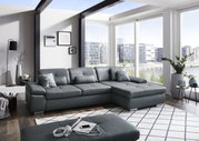 Moderne Longchairkombination in einem hellen Wohnzimmer mit großen Fenstern und Blick auf die Stadt. Perspektive von vorne links.