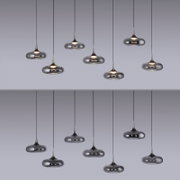 Mehrere moderne Pendelleuchten mit rauchgrauem, spiegelndem Glas-Schirm und warmem Licht hängen an schwarzen Kabeln vor grauem Hintergrund, Frontalansicht.