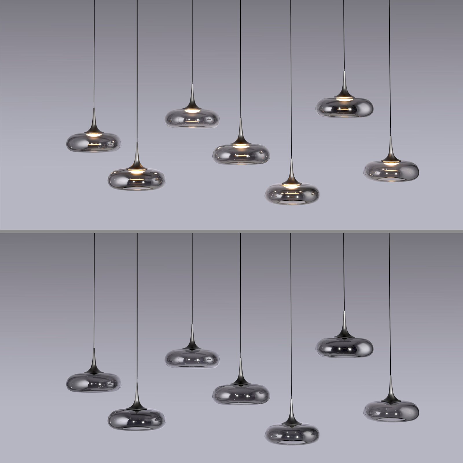 Mehrere moderne Pendelleuchten mit rauchgrauem, spiegelndem Glas-Schirm und warmem Licht hängen an schwarzen Kabeln vor grauem Hintergrund, Frontalansicht.