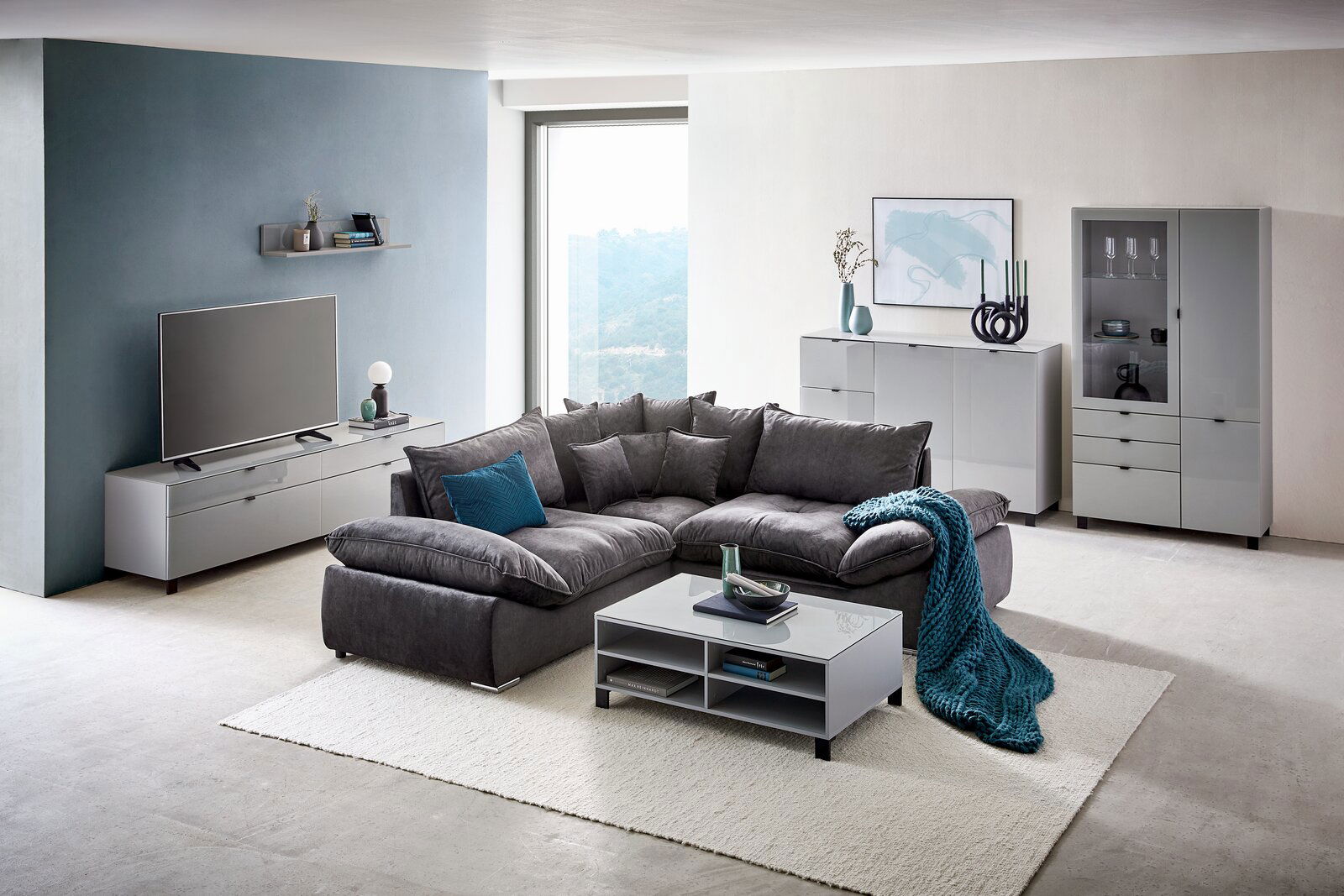 Modernes Wohnzimmer mit TV-Lowboard in Frontansicht, grauem Sofa und stilvoller Dekoration.
