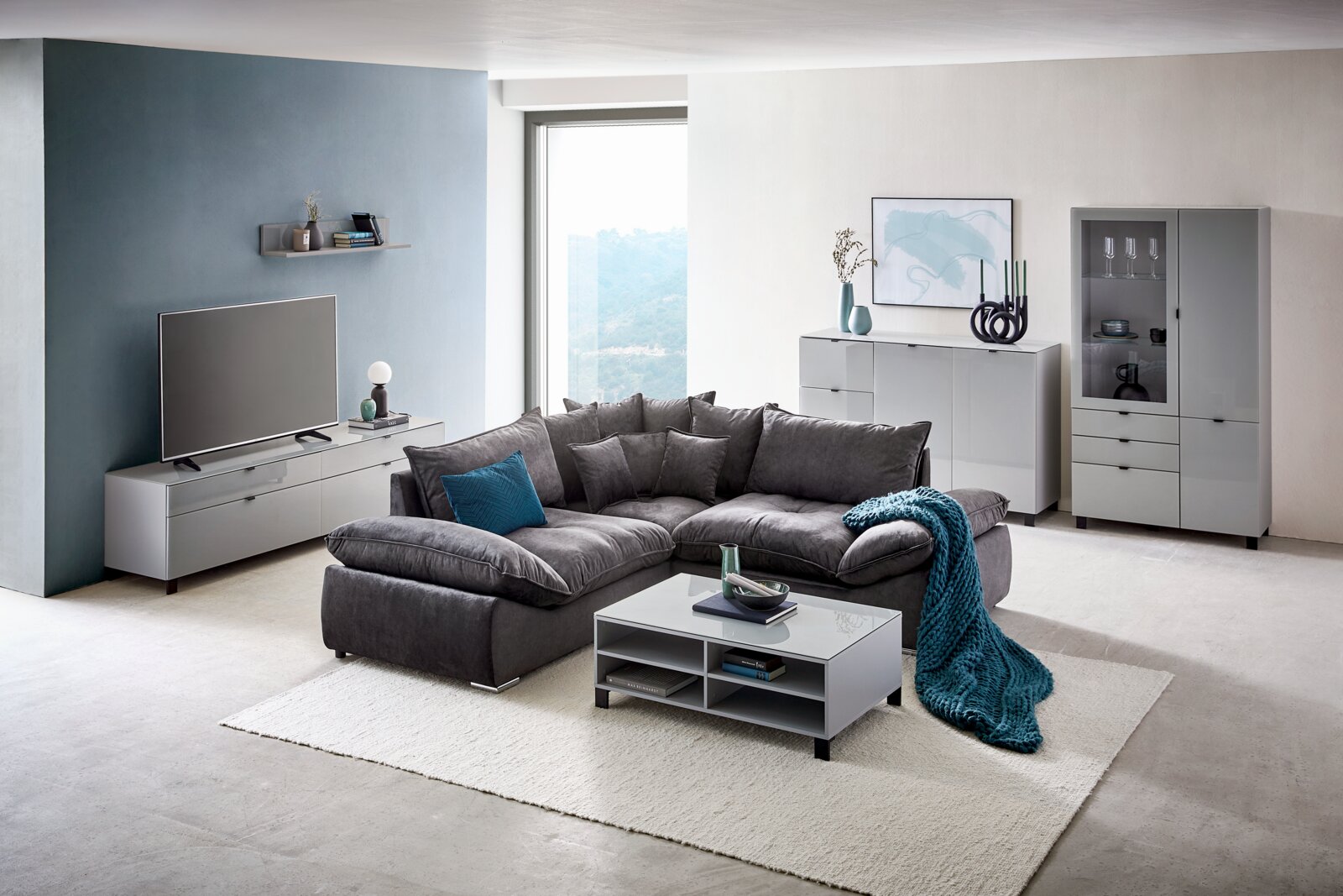 Moderne woonkamer met tv-kast in vooraanzicht, grijze bank en stijlvolle decoratie.