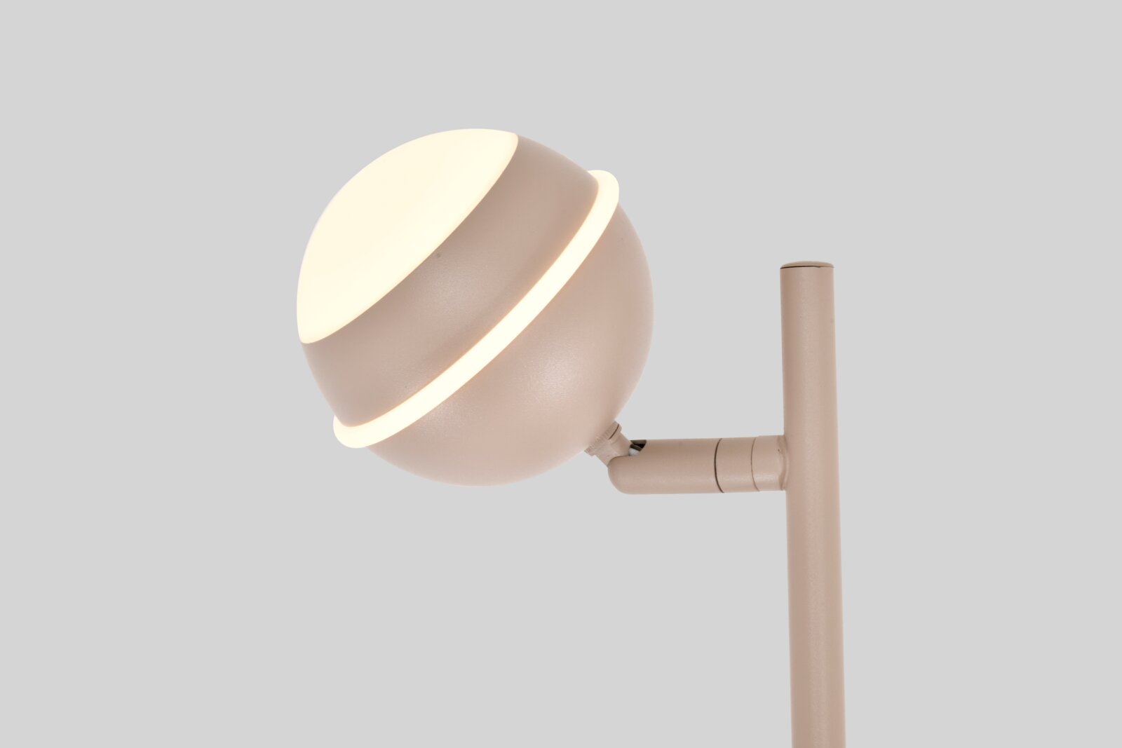 Close-up in zijaanzicht van een moderne beige lamp met kantelbare bolvormige kap en warmwitte lichtaccenten