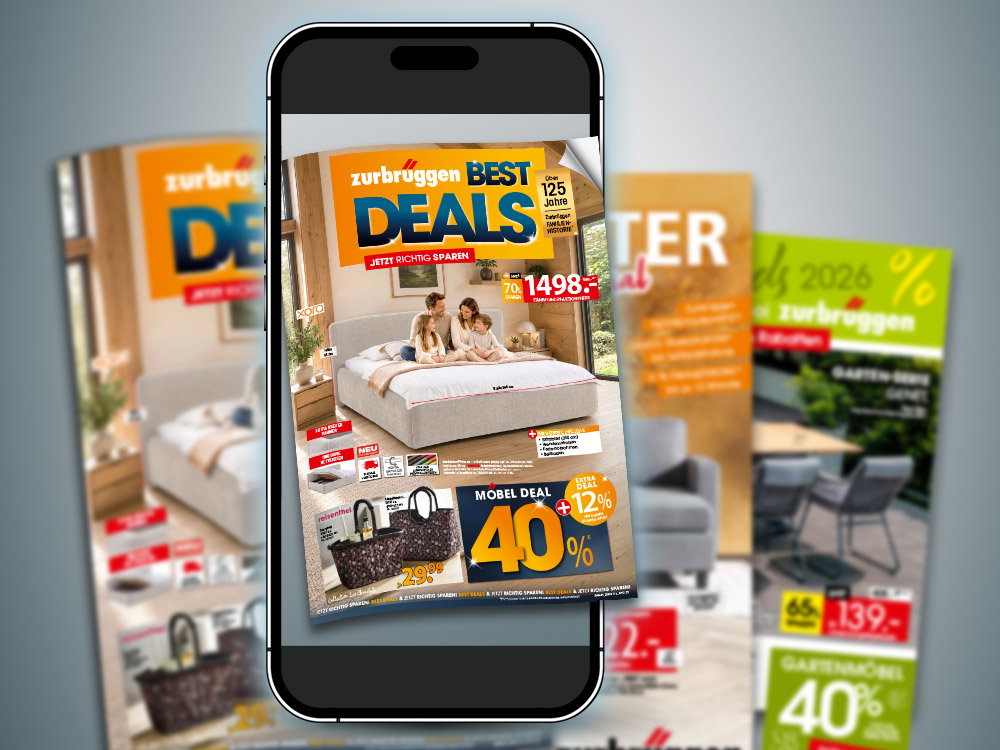 Smartphone mit digitalem Zurbrüggen-Prospekt „Best Deals“ mit Bett und Rabattangeboten, weitere Prospekte im Hintergrund.