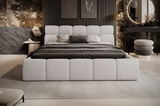 Modernes Polsterbett in einem stilvollen Schlafzimmer, frontal aufgenommen. Das Bett hat ein gepolstertes Kopf- und Fußteil in hellem Stoff, umgeben von eleganter Dekoration und Beleuchtung.