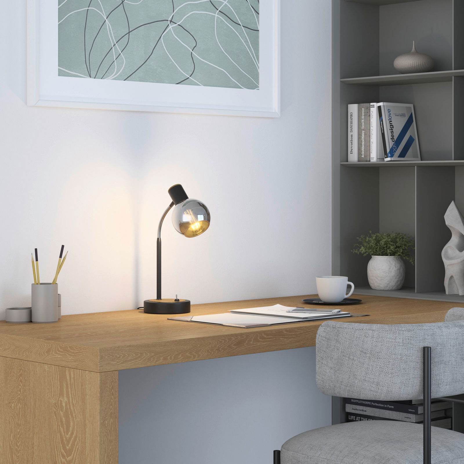 Moderne Tischleuchte mit gebogenem Hals und kugelförmigem Lampenschirm auf einem Schreibtisch, seitliche Perspektive.