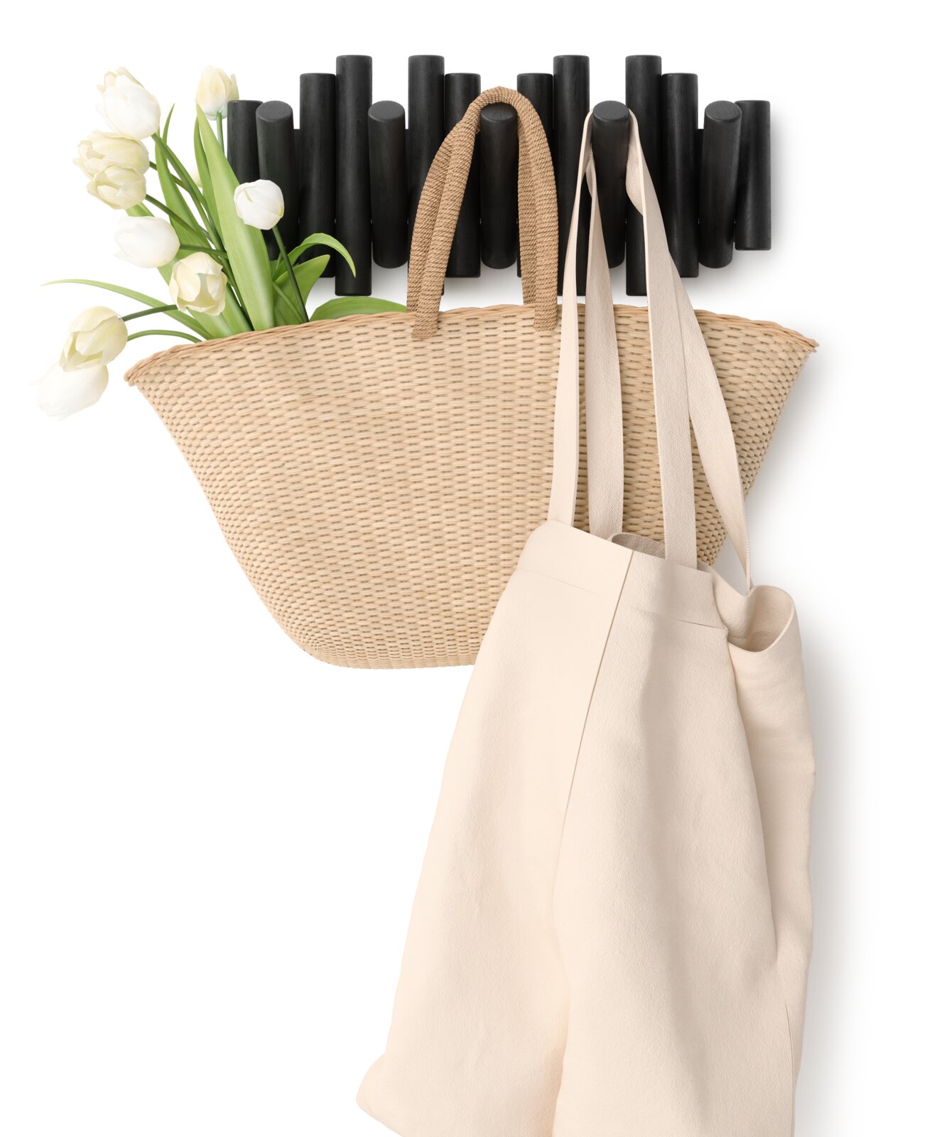 Wandgarderobe mit schwarzem, modernem Design, darauf hängend ein geflochtener Korb mit weißen Tulpen und eine beige Stofftasche, seitliche Perspektive.