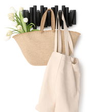 Wandgarderobe mit schwarzem, modernem Design, darauf hängend ein geflochtener Korb mit weißen Tulpen und eine beige Stofftasche, seitliche Perspektive.