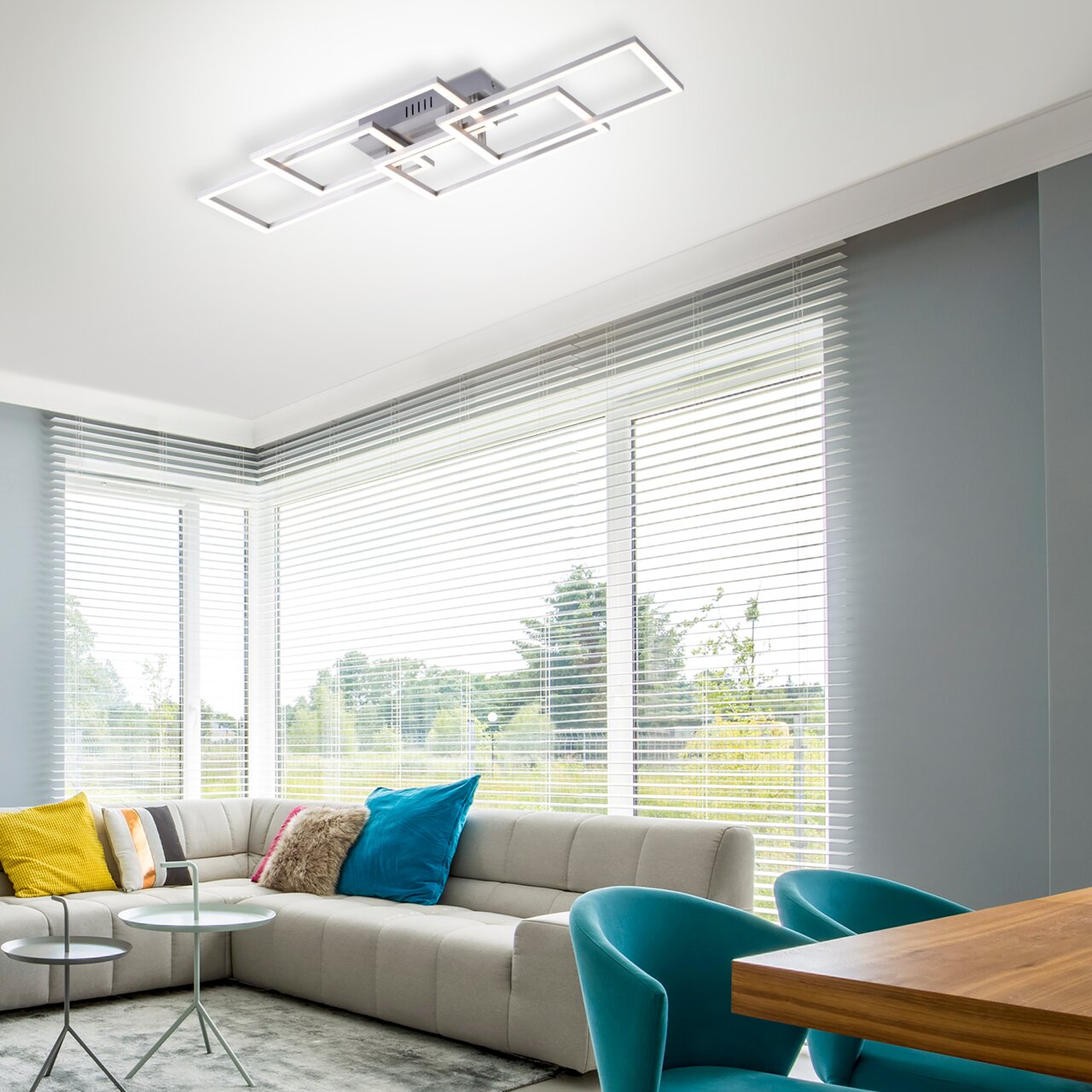 Moderne Deckenleuchte IVEN in geometrischem Design, von unten betrachtet in einem stilvollen Wohnzimmer mit großen Fenstern.