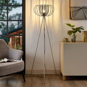 Moderne Stehleuchte mit dreibeinigem Stativ und dekorativem Lampenschirm in einem gemütlichen Wohnzimmer, seitliche Perspektive.