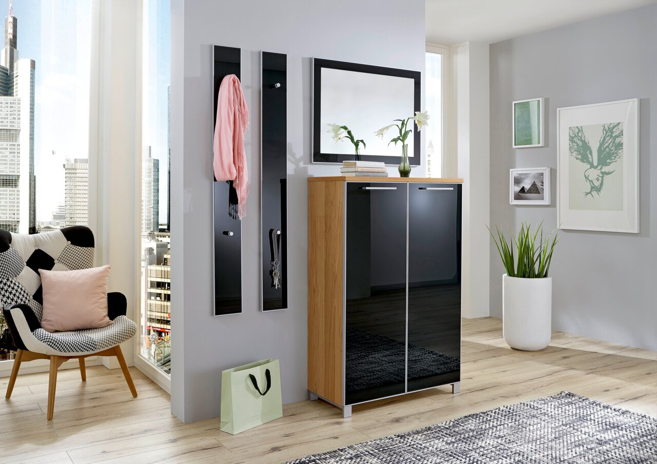 Modernes Garderoben-Set in einem hellen Raum mit Stadtblick, bestehend aus einem Schrank mit zwei Türen, zwei Wandpaneelen mit Haken und einem Spiegel. Perspektive von vorne.