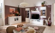 Moderne Wohnzimmeransicht mit einer weißen Vitrine links, dekoriert mit Gläsern und Pflanzen, in einem stilvoll eingerichteten Raum.