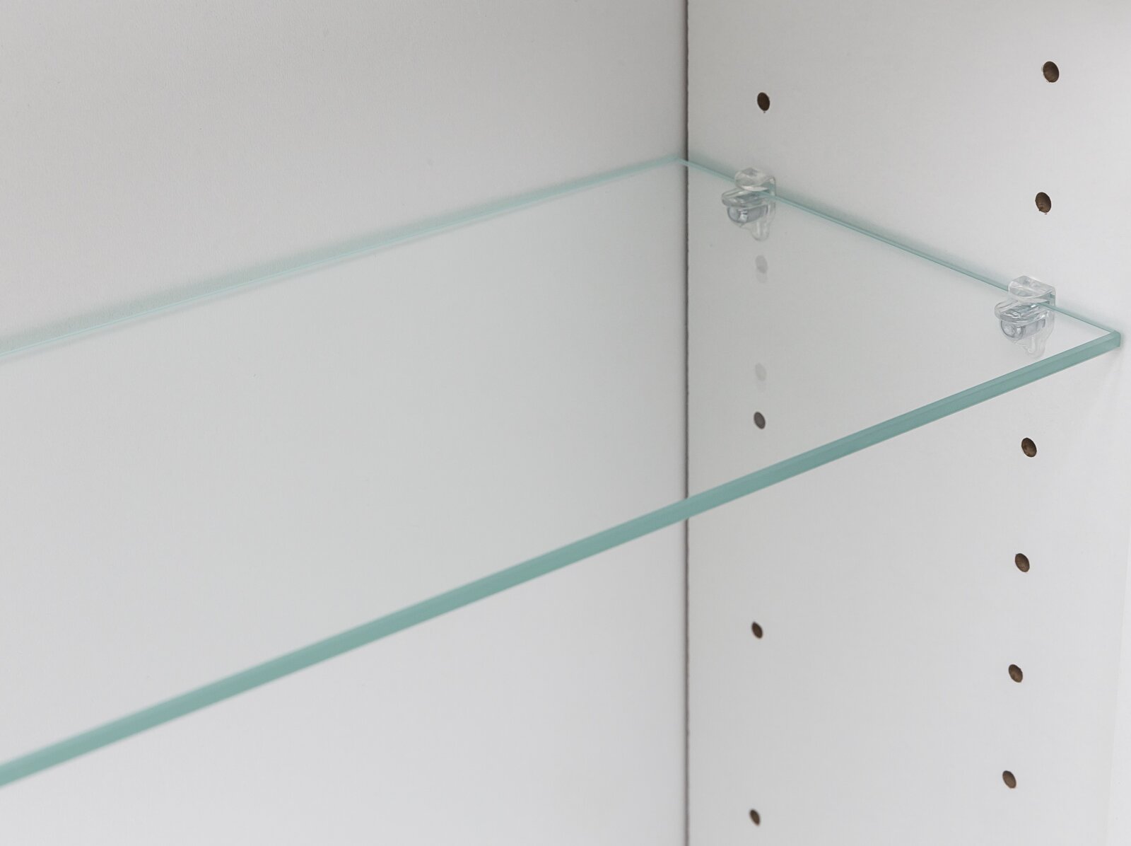 Transparenter Glasboden mit Halteclips in einem weißen Regal, Detailansicht aus schräger Seitenperspektive