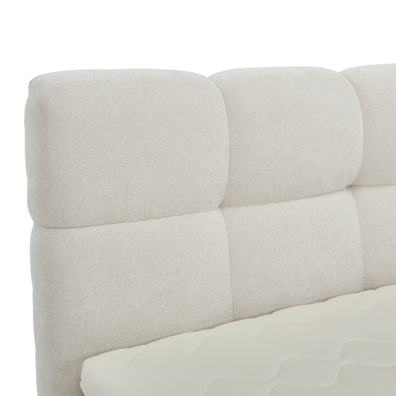 Nahaufnahme eines gepolsterten, cremefarbenen Boxbett-Kopfteil mit weicher Textur, seitliche Perspektive