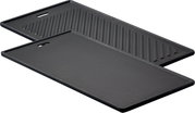 Zwei schwarze Grillplatten, eine mit glatter Oberfläche und eine mit geriffelter Oberfläche, in schräger Perspektive.