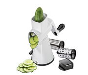 Trommelreibe Rapid mit einer Gurke in der Trommel, geschnittene Gurkenscheiben davor, zwei zusätzliche Trommeln und ein schwarzer Schieber, seitliche Perspektive.