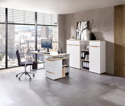 Moderne Büroumgebung mit weißem Schreibtisch, Rollcontainer und Aktenschrank, seitliche Perspektive.