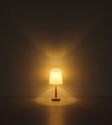 Stehleuchte mit warmem Licht, frontal betrachtet, auf einem dunklen Hintergrund.