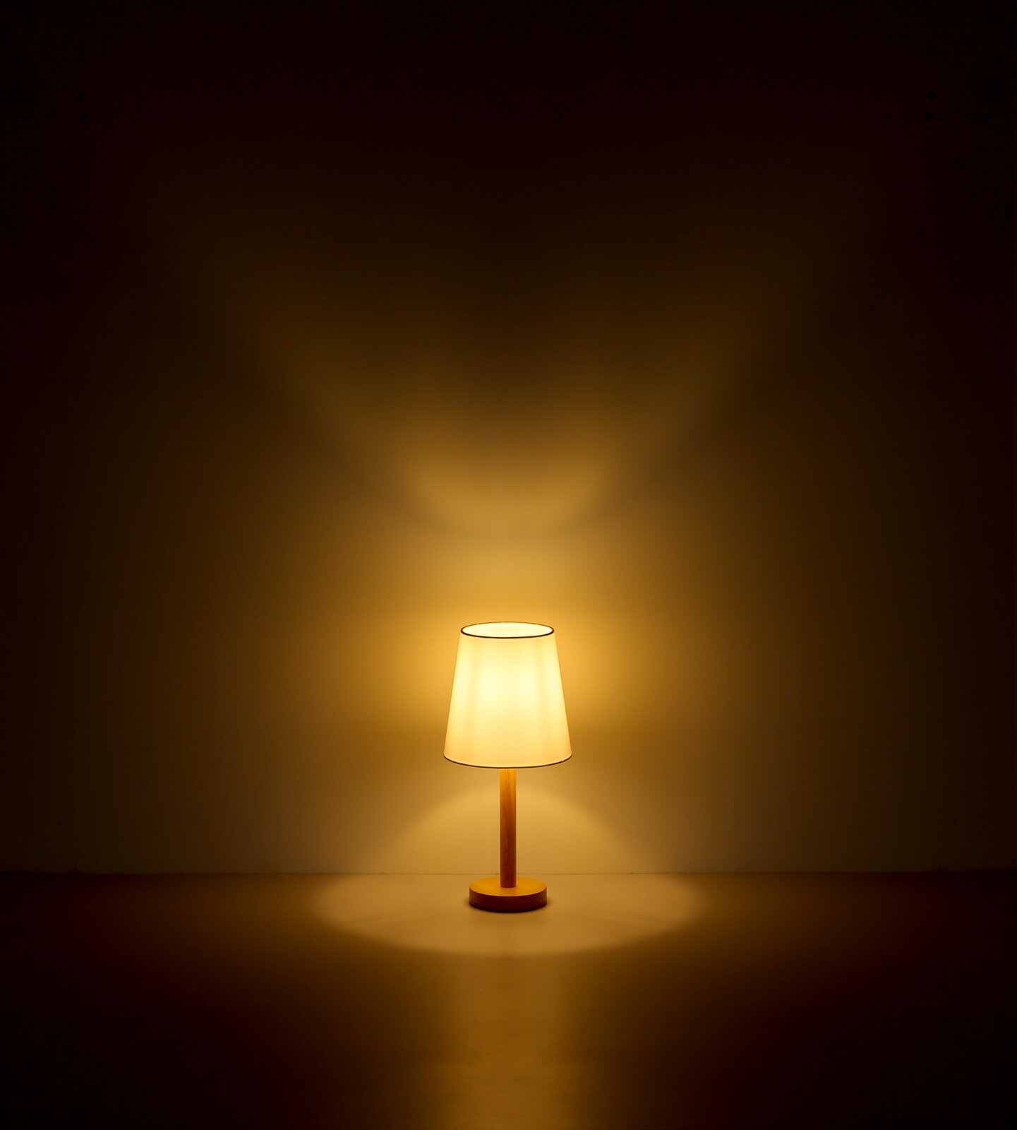 Stehleuchte mit warmem Licht, frontal betrachtet, auf einem dunklen Hintergrund.