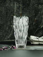 Kristallvase mit facettiertem Design, frontal fotografiert, auf einem dunklen Hintergrund mit dekorativen Elementen.