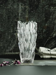 Kristallvase mit facettiertem Design, frontal fotografiert, auf einem dunklen Hintergrund mit dekorativen Elementen.