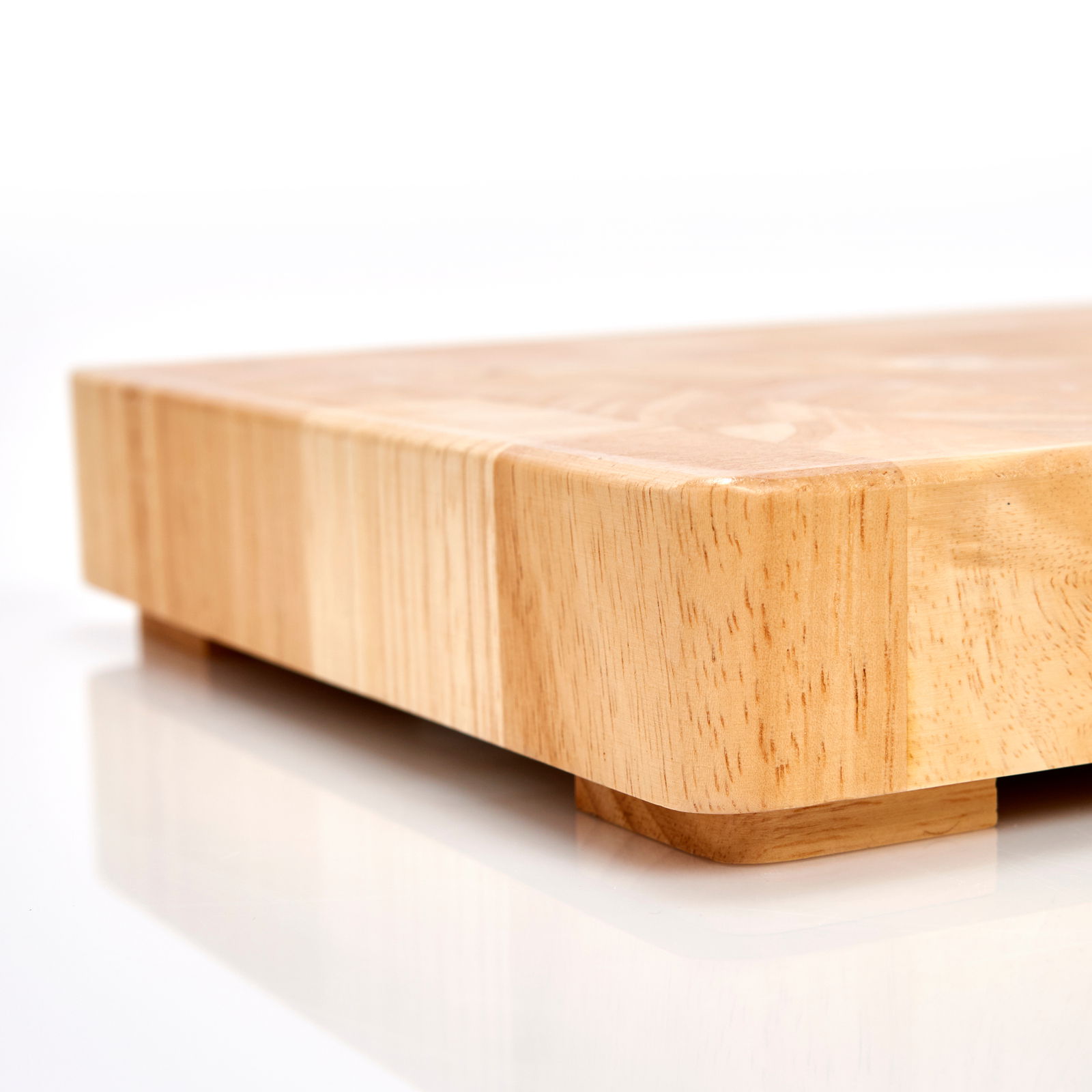 Nahaufnahme eines massiven Hackblocks aus Holz mit glatter Oberfläche und abgerundeten Ecken, seitliche Perspektive.