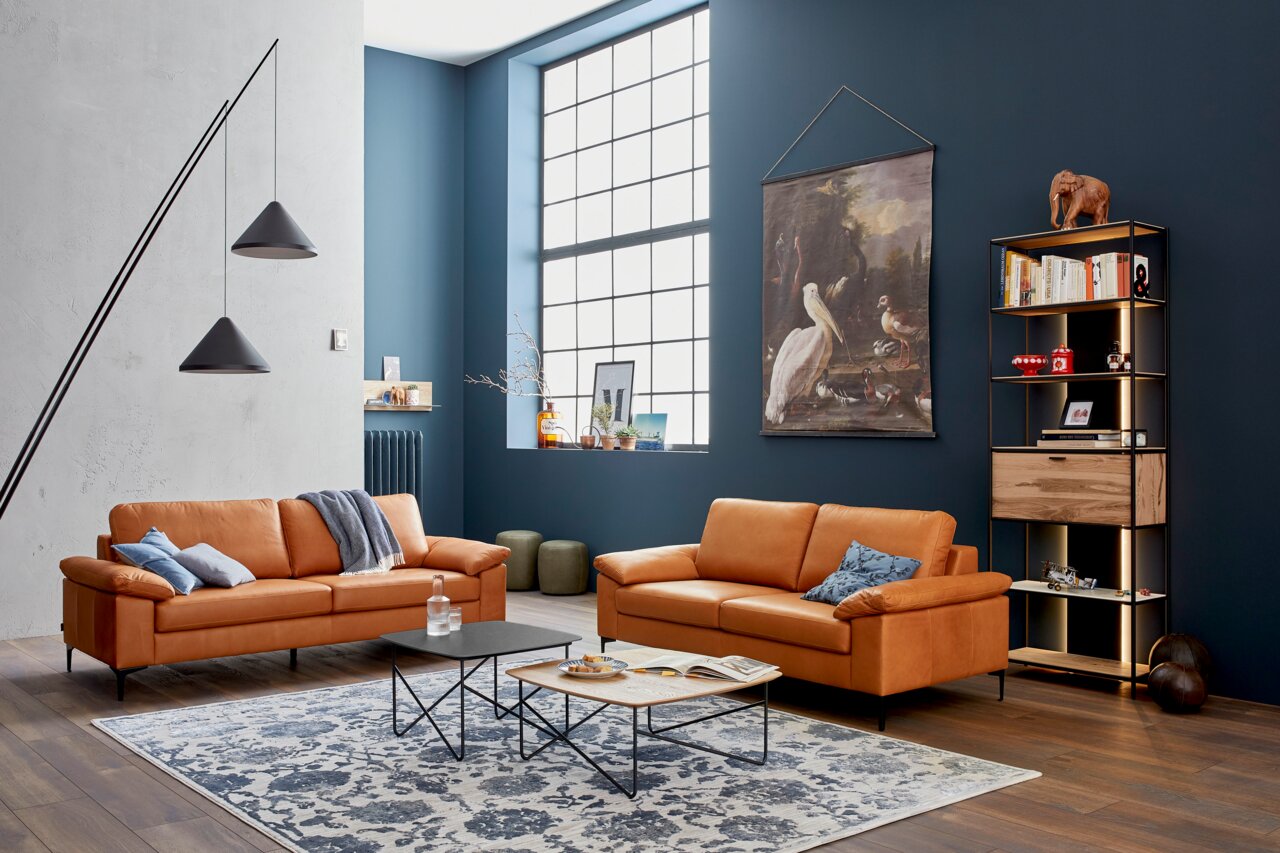 Moderner Couchtisch in einem stilvollen Wohnzimmer mit Ledersofas und dekorativen Elementen, seitliche Perspektive.