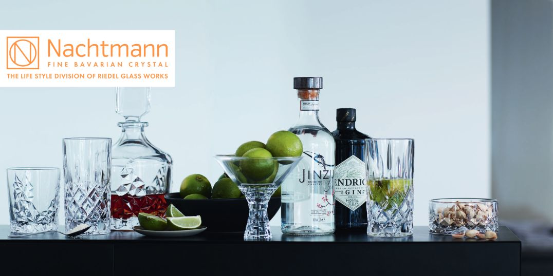 Een presentatie van kristallen glazen met sterke drank, limoenen en noten, van het merk Nachtmann.