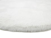Nahaufnahme eines weißen, flauschigen Fellteppichs aus seitlicher Perspektive.