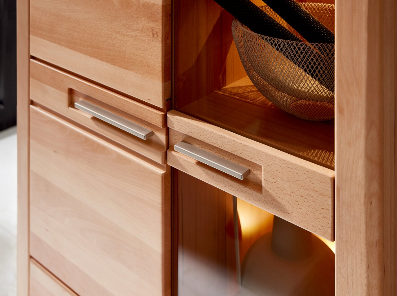 Nahaufnahme einer hölzernen Vitrine mit modernen Metallgriffen, seitliche Perspektive.