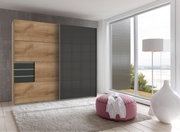 Moderner Schwebetürenschrank mit Holz- und Grautönen, seitliche Perspektive, in einem hellen Raum mit großen Fenstern.