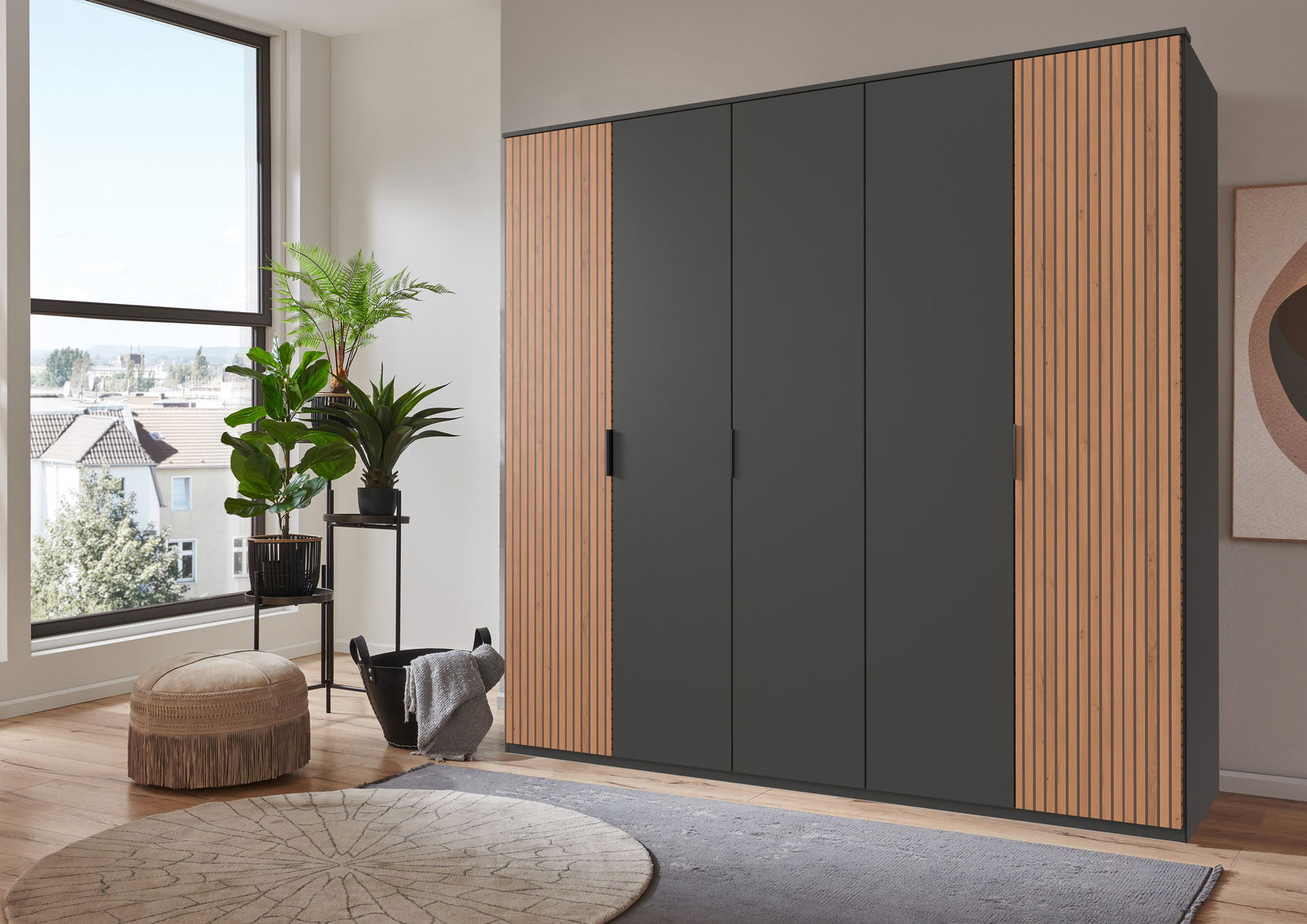 Z2 Drehtürenschrank 5-trg. Tunis Moderner 5-türiger Drehtürenschrank in einem stilvollen Raum, frontal betrachtet. Der Schrank hat eine dunkle Oberfläche mit Holzdetails an den Seiten.