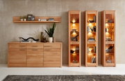 Schmale Vitrine aus Holz mit Glasfronten, beleuchtet, gefüllt mit dekorativen Objekten, aus frontaler Perspektive.