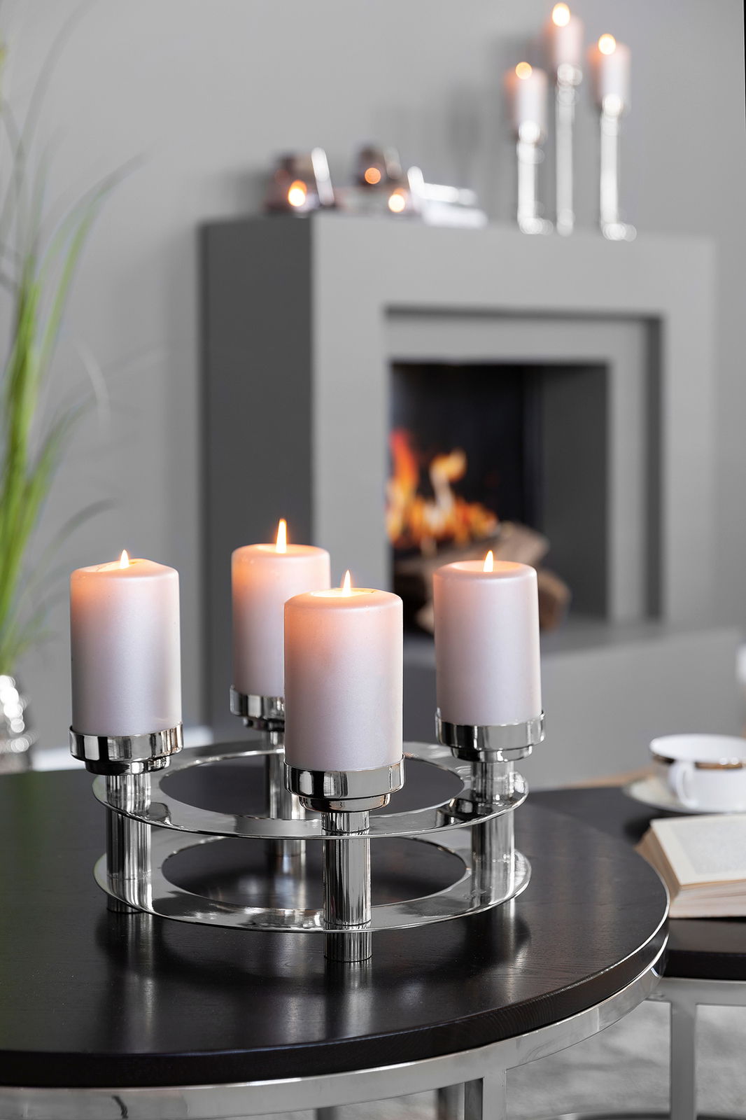 Moderner vierflammiger Kerzenhalter aus Metall mit brennenden Kerzen, auf einem Tisch in einem stilvollen Wohnzimmer platziert, seitliche Perspektive.